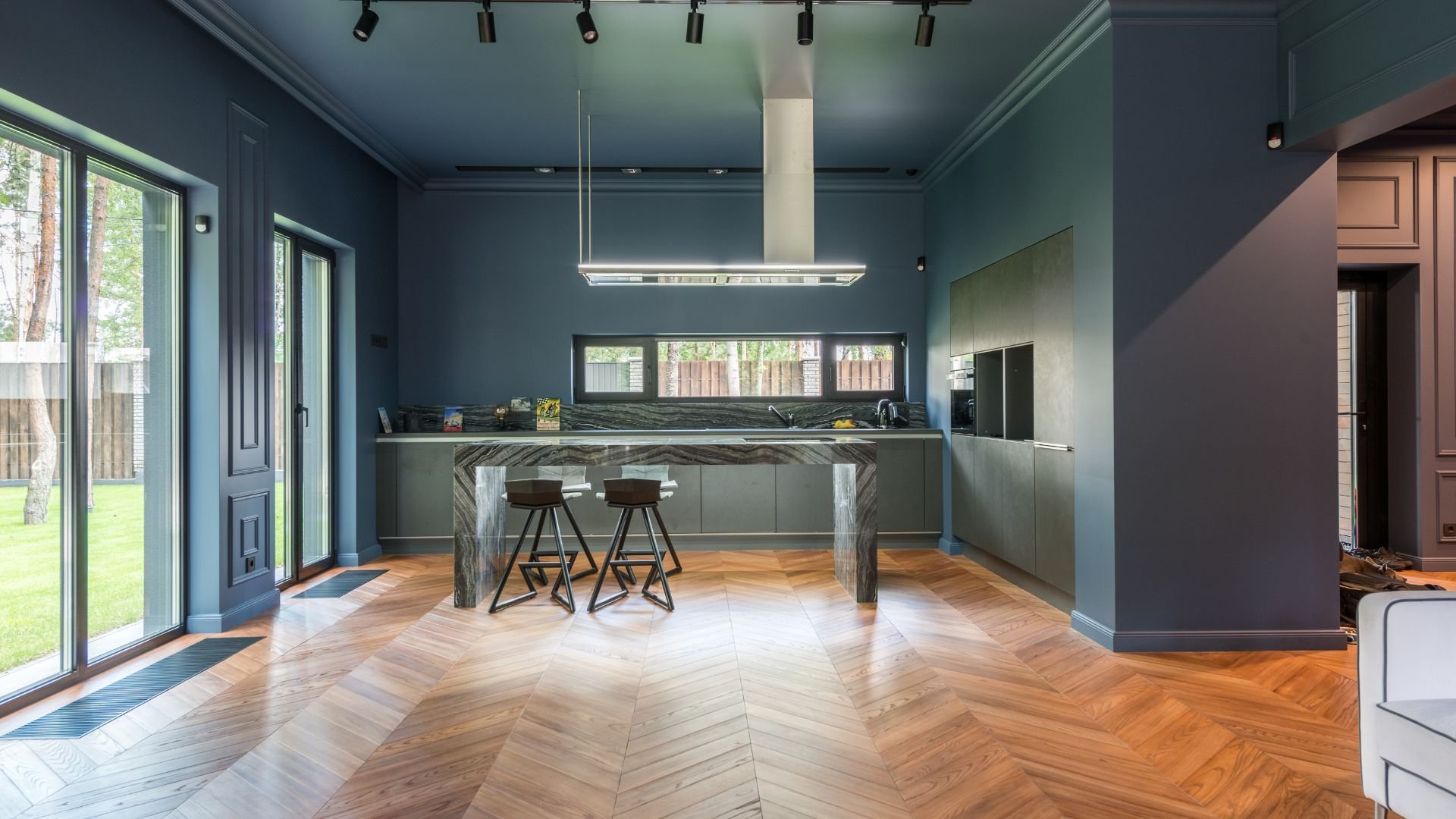 Modern blue kitchen with herringbone wood floor and large windows