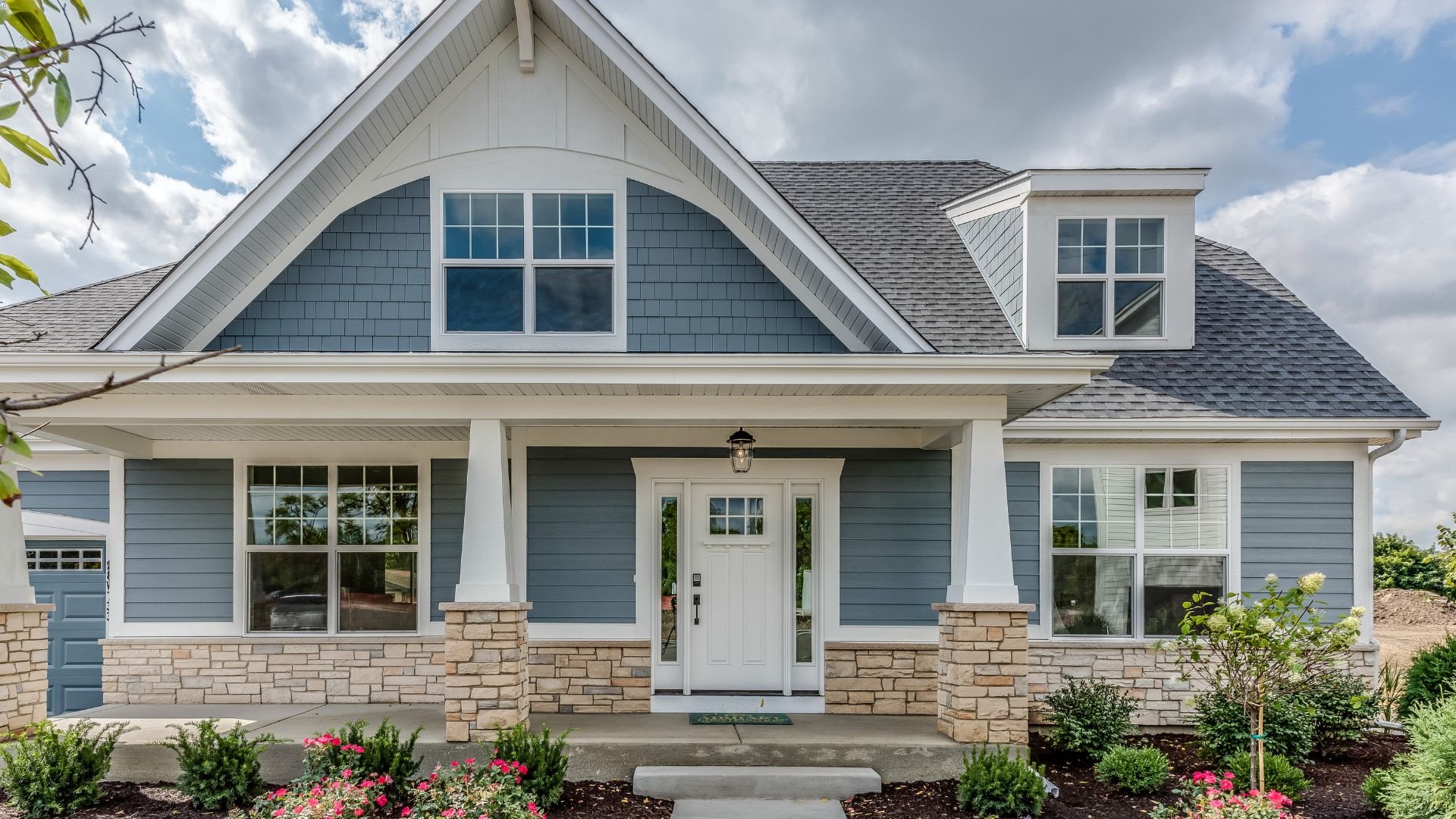 Craftsman-style home with blue siding, white trim, and stone foundation