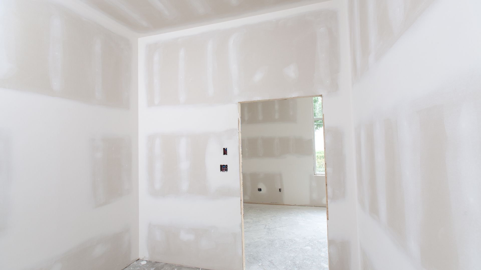 Unfinished room with drywall and open doorway leading to another room